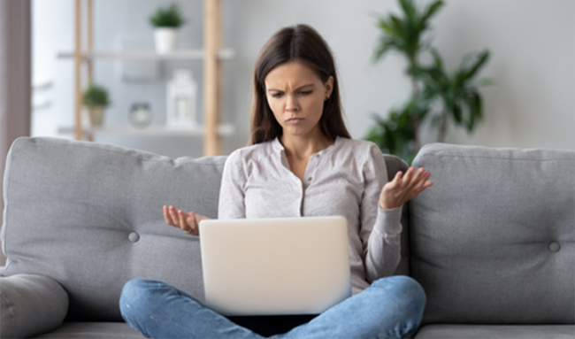 Frau auf Sofa mit Computer fordert Schadenersatz